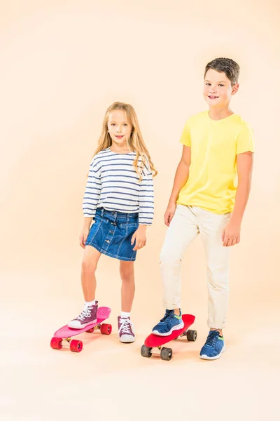 Full length view of two smiling kids with skateboards on pink — Stock Photo