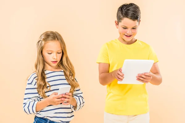 Дві дитини використовують смартфон і цифровий планшет ізольовані на рожевому — стокове фото