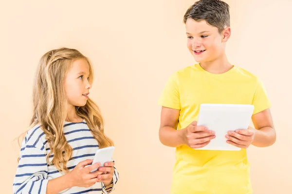 Two kids using smartphone and digital tablet isolated on pink — Stock Photo