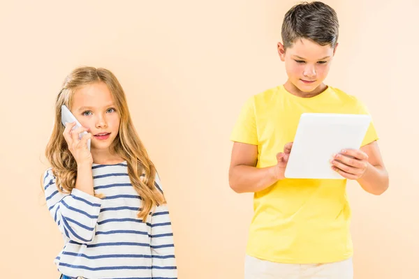 Two kids using smartphone and digital tablet isolated on pink — Stock Photo