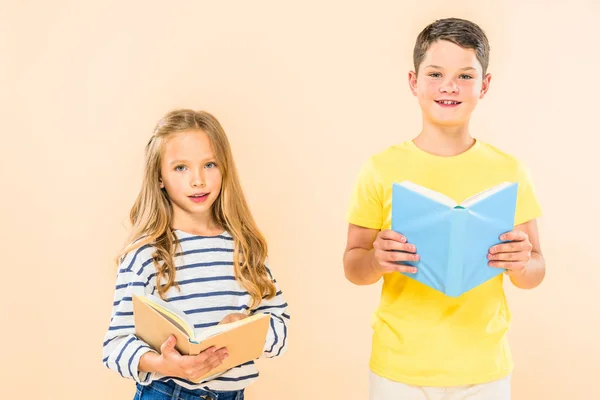 Vista frontal de dos niños sonrientes sosteniendo libros aislados en rosa - foto de stock