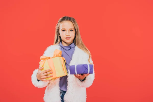 Front view of kid holding gift boxes isolated on red — Stock Photo