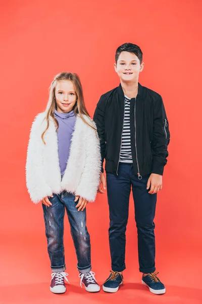 Vue pleine longueur de deux enfants souriants sur rouge — Photo de stock