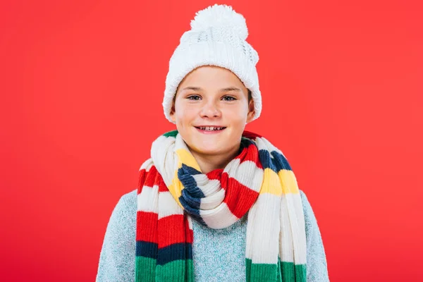 Вид спереди улыбающегося малыша в шляпе и шарфе, изолированного на красный — стоковое фото