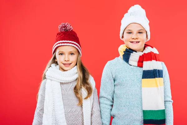 Vista frontal de dos niños en trajes de invierno aislados en rojo - foto de stock