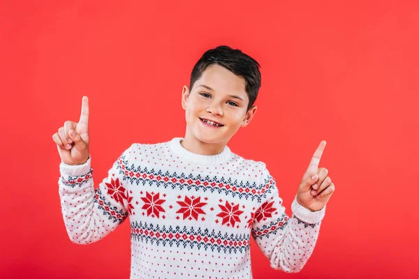 Front view of smiling kid in sweater pointing with fingers isolated on red — Stock Photo