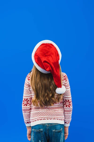 Vista trasera de niño en suéter y sombrero de santa aislado en azul - foto de stock