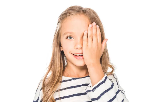 Vista frontal de niño sonriente que cubre el ojo con la mano aislada en blanco - foto de stock