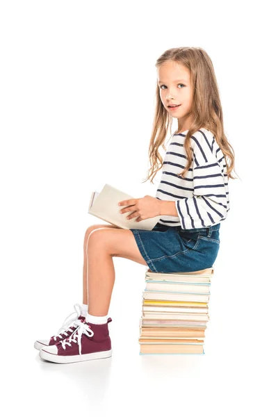 Kid in denim skirt sitting on books and reading on white — Stock Photo