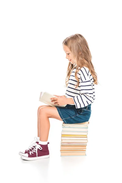 Kid in denim skirt sitting on books and reading on white — Stock Photo