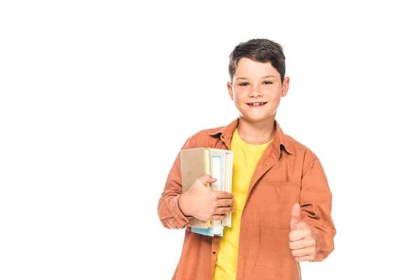 Vista frontal del niño sonriente sosteniendo libros y mostrando el pulgar hacia arriba aislado en blanco - foto de stock