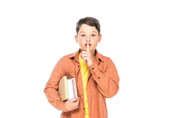 Frontansicht eines Kindes, das Bücher hält und Schweigegegeste zeigt, isoliert auf Weiß — Stockfoto