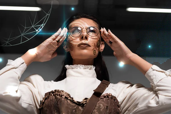 Low angle view of steampunk woman with makeup touching glasses — Stock Photo