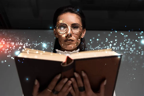 Низкий угол обзора стемпанка в очках, читающего книгу с перчаточным рисунком выше — стоковое фото