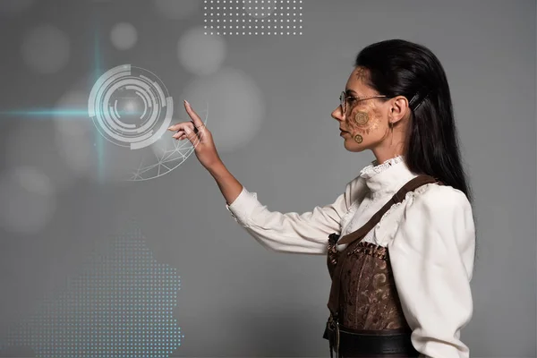 Cropped view of steampunk young woman in white blouse pointing with finger at digital illustration on grey — Stock Photo
