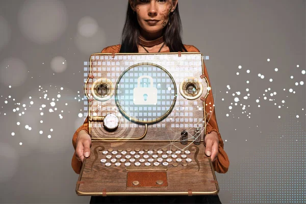 Vista cortada de mulher steampunk em chapéu superior com óculos mostrando laptop vintage com ilustração de segurança na internet isolado em cinza — Fotografia de Stock