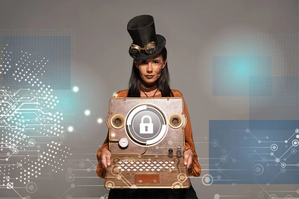 Steampunk woman in top hat with goggles showing vintage laptop with internet security illustration isolated on grey — Stock Photo