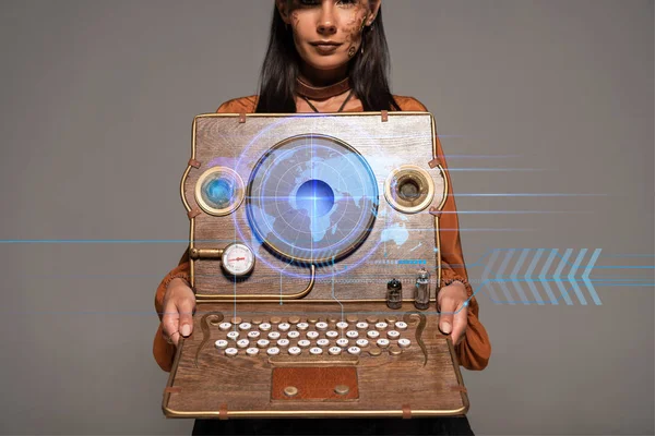 Cropped view of steampunk woman in top hat with goggles showing vintage laptop with digital map isolated on grey — Stock Photo