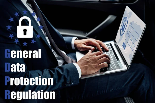 Partial view of african american businessman using laptop in car with gbpr illustration — Stock Photo