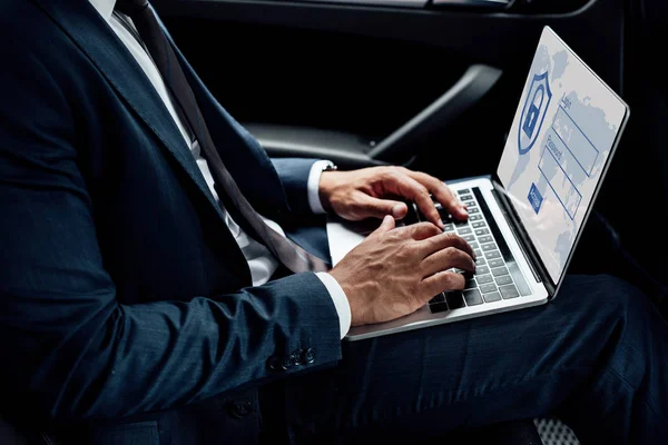 Teilansicht eines afrikanisch-amerikanischen Geschäftsmannes, der Laptop mit Internet-Sicherheitsabbildung im Auto benutzt — Stockfoto