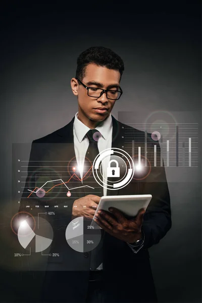 African american businessman in glasses using digital tablet on dark background with internet security illustration — Stock Photo