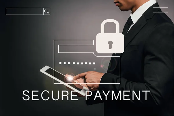 Partial view of african american businessman using digital tablet on dark background with secure payment illustration — Stock Photo
