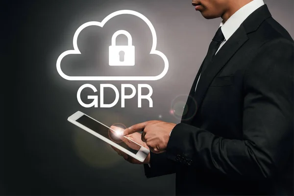 Vista parcial del hombre de negocios afroamericano usando tableta digital sobre fondo oscuro con ilustración gdpr — Stock Photo