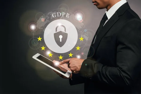 Partial view of african american businessman using digital tablet on dark background with gdpr illustration — Stock Photo
