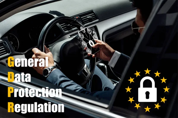 Hombre de negocios afroamericano en traje y gafas de sol coche de conducción y el uso de teléfono inteligente con ilustración gdpr - foto de stock