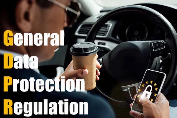Back view of african american businessman using smartphone and drinking coffee in car with gdpr illustration — Stock Photo