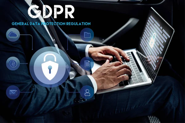 Partial view of african american businessman using laptop with gdpr illustration in car — Stock Photo