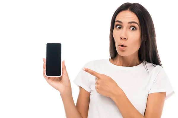 Femme choquée pointant du doigt le smartphone avec écran blanc isolé sur blanc — Photo de stock