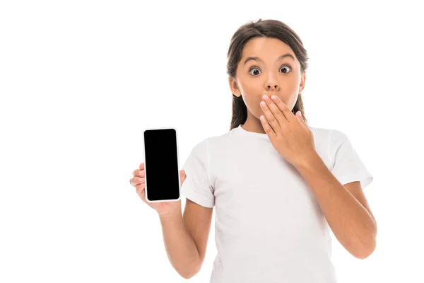 Niño sorprendido sosteniendo teléfono inteligente con pantalla en blanco aislado en blanco - foto de stock