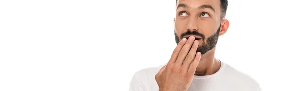 Панорамный снимок удивленного человека, закрывающего рот изолированным на белом — стоковое фото