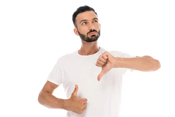 Hombre pensativo mostrando el pulgar hacia arriba y el pulgar hacia abajo aislado en blanco - foto de stock