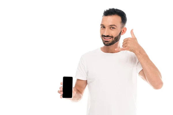 Hombre barbudo que muestra el signo de llamada mientras sostiene el teléfono inteligente con pantalla en blanco aislado en blanco - foto de stock