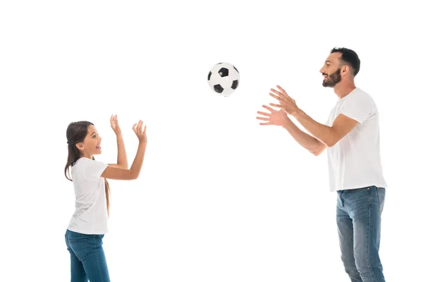 Vista lateral de feliz padre lanzando en el aire de fútbol cerca de hija aislada en blanco - foto de stock