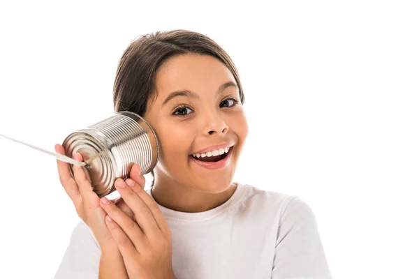 Criança feliz segurando lata perto da orelha isolada no branco — Fotografia de Stock