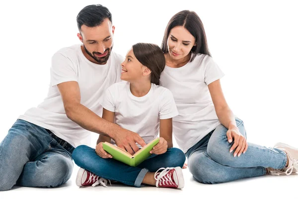 Веселый отец сидит и показывает пальцем на книгу рядом с семьей изолированы на белом — стоковое фото