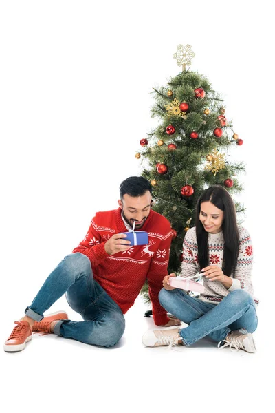 Cheerful man and happy woman holding gifts near christmas tree isolated on white — Stock Photo