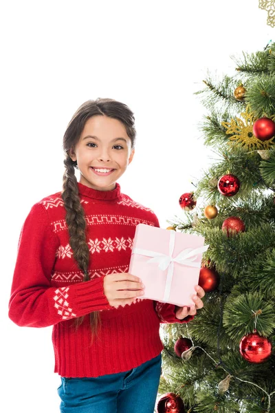 Allegro bambino che tiene il regalo rosa vicino all'albero di Natale isolato su bianco — Foto stock