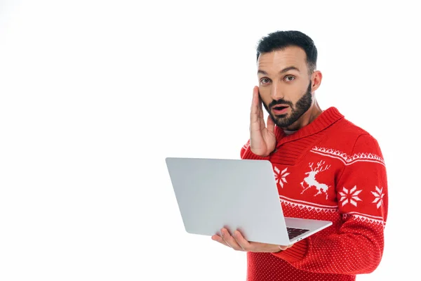 Здивований бородатий чоловік в светрі використовує ноутбук ізольований на білому — стокове фото
