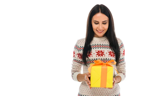 Cheerful woman in sweater looking at gift box isolated on white — Stock Photo