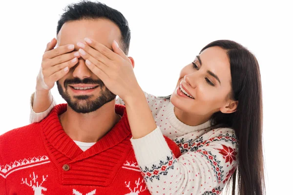 Mujer feliz cubriendo los ojos del hombre barbudo en suéter aislado en blanco - foto de stock