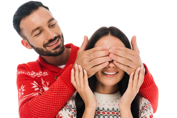 Hombre barbudo alegre cubriendo los ojos de la mujer en suéter aislado en blanco - foto de stock