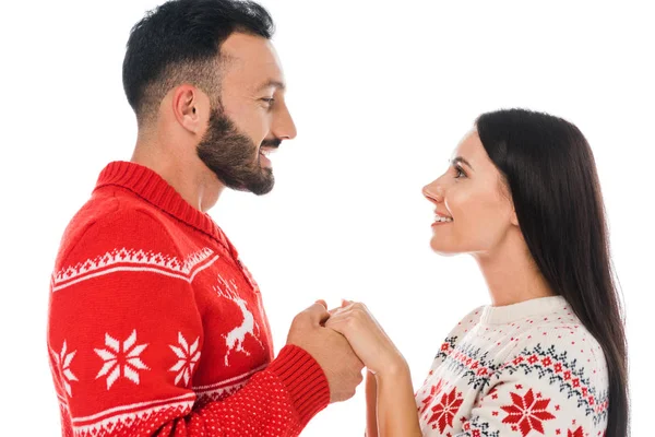 Vista laterale di allegro uomo barbuto che si tiene per mano di donna sorridente in maglione isolato su bianco — Foto stock