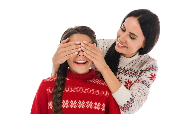 Mulher alegre que cobre olhos da filha feliz no suéter isolado no branco — Fotografia de Stock
