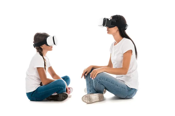 Mother and daughter using virtual reality headsets while sitting on white — Stock Photo