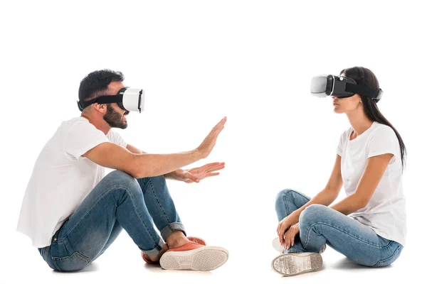 Uomo gesticolando vicino donna mentre si utilizza cuffia realtà virtuale su bianco — Foto stock