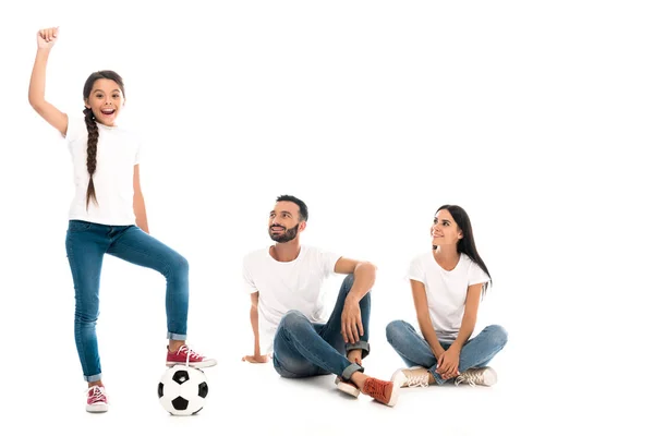 Bambino felice con mano sopra la testa in piedi vicino al calcio e genitori su bianco — Foto stock